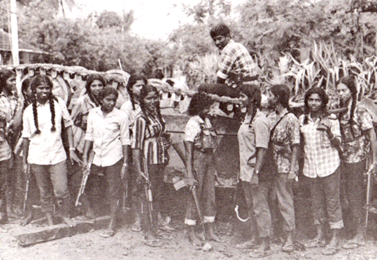 LTTE Women Guerrillas stand victorious in front of an Indian Army tank destroyed by them